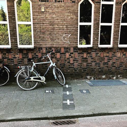Bicycle parked near border markings in Baarle where national boundaries pass through the street.